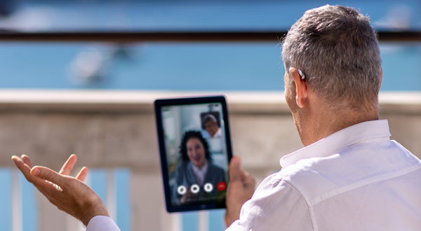 Älterer Herr mit Hörgerät telefoniert via Videochat mit einer Frau. 